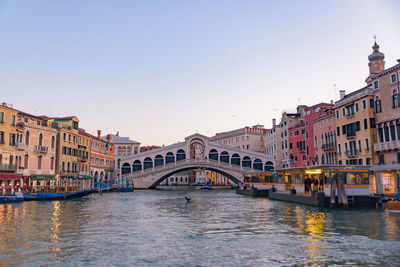 Bridge over canal in city against clear sky