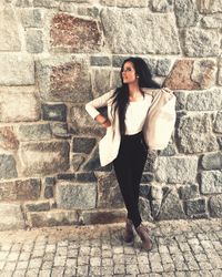 Portrait of woman standing against brick wall