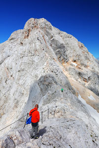 Rear view of person on rock by mountain against sky