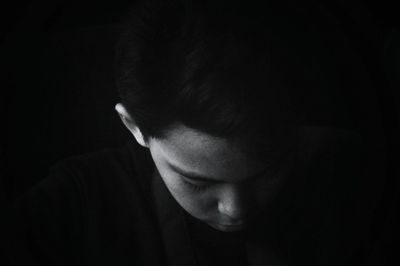 Close-up of thoughtful boy against black background