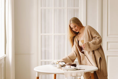 A beautiful blonde young woman in a knitted sweater celebrates the christmas holiday at home