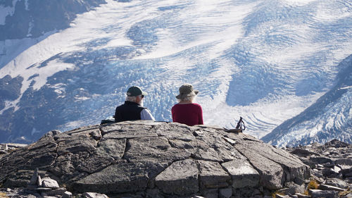 Rear view of people sitting on snowcapped mountain