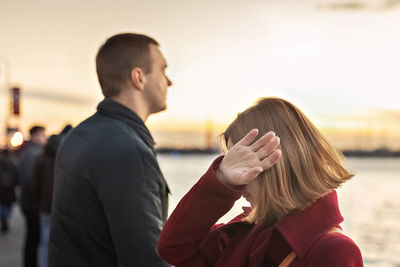 Young couple man and woman in a quarrel, on the embankment of the river in the city 