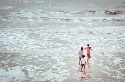 Rear view of people walking in calm sea