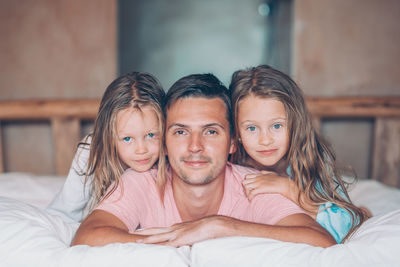 Portrait of father with daughters on bed