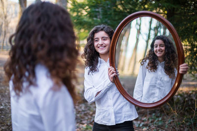 Smiling young woman standing against wall