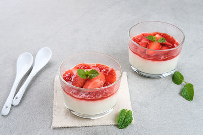 Sweet vanilla silky pudding dessert with strawberry sauce, sliced fresh strawberries and mint