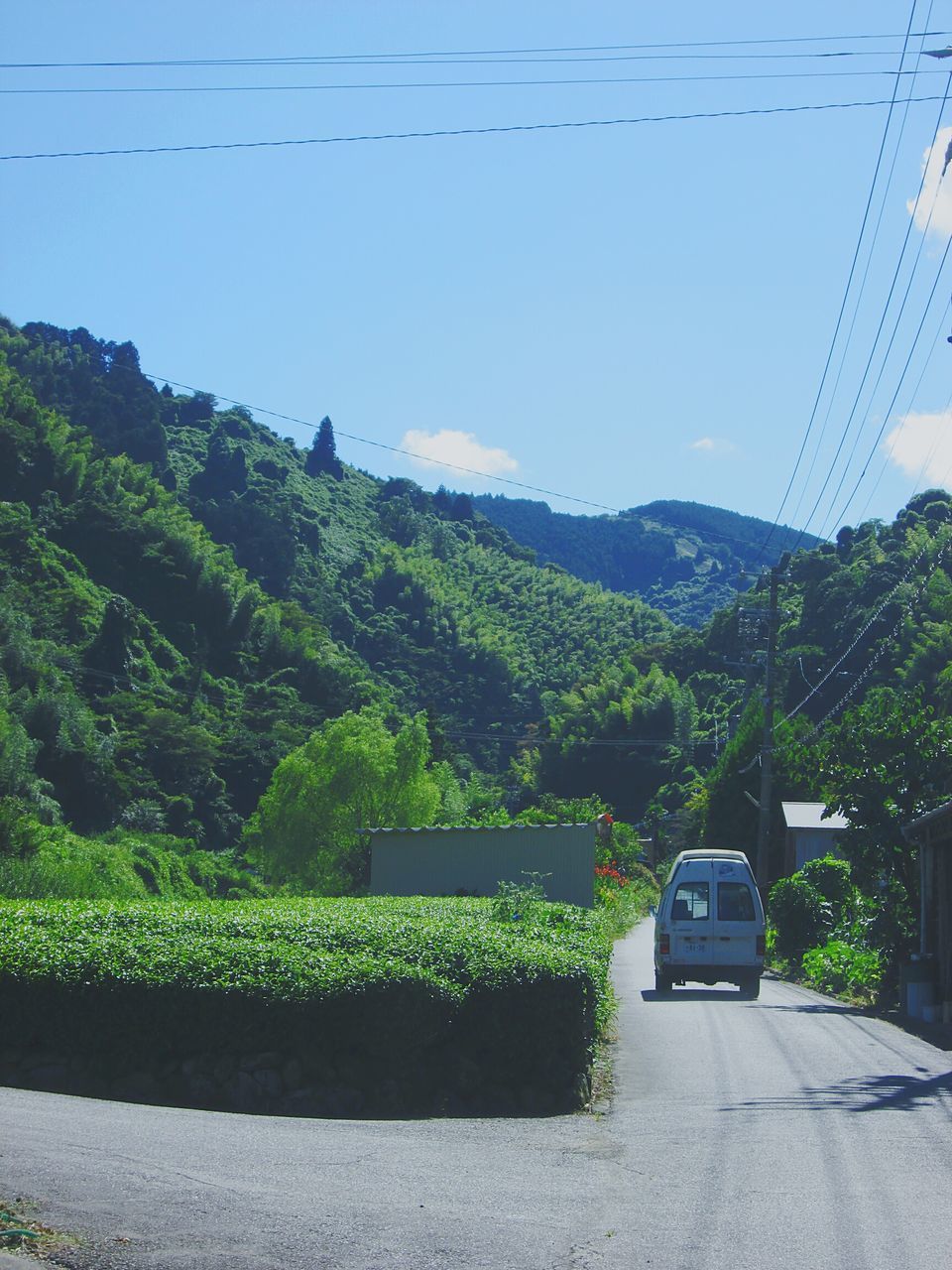 clear sky, mountain, transportation, tree, power line, road, landscape, electricity pylon, cable, car, nature, land vehicle, mountain range, tranquility, mode of transport, green color, tranquil scene, blue, growth, sky