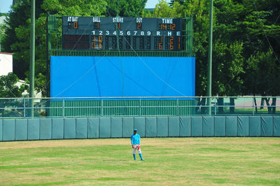 Rear view of man playing soccer on field