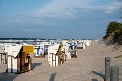 Deck chairs on beach against sky