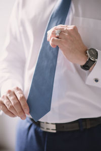 Midsection of businessman holding necktie