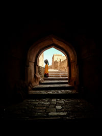 Man standing at archway of old building