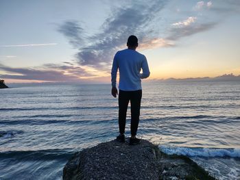 Rear view of man looking at sea against sky