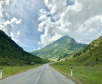 Road leading towards mountains against sky