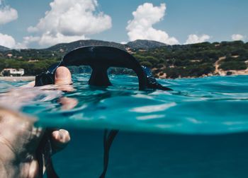 Cropped hand of man holding scuba mask in sea