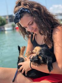 Young woman carrying puppy while sitting by river