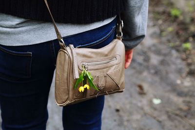 Close-up of woman carrying purse with yellow flowers