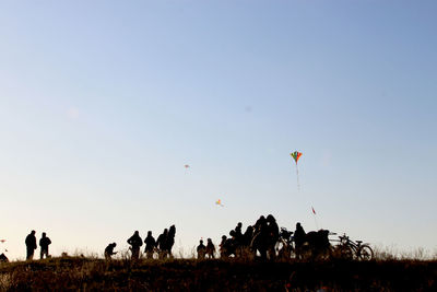 Silhouette people at field against clear sky