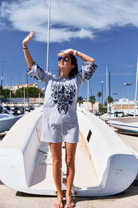 Smiling young woman shielding eyes while standing at harbor