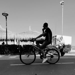 Side view of man riding bicycle on street