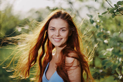 Portrait of young woman standing against plants