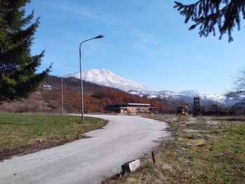 Road amidst field and mountains against sky