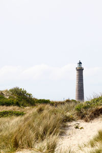 Lighthouse on beach against sky