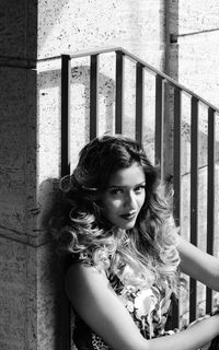 Portrait of woman looking down while sitting on railing