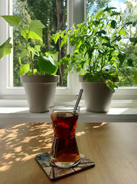 A cup of traditional turkish tea on a wooden table and two house plants in the background 