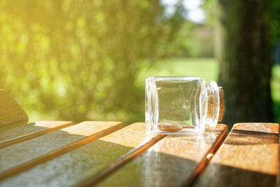 Transparent small bottle with coins on bench