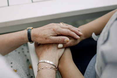 Midsection of senior man and female nurse holding hands at retirement home