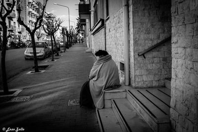 Rear view of man sitting outside building