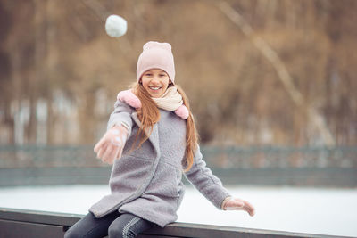 Portrait of smiling young woman sitting on railing