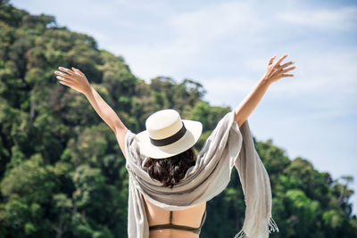 Rear view of woman with arms raised against sky