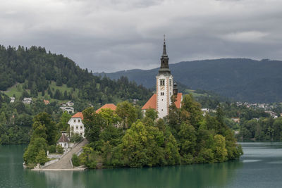 Scenic view of river by buildings against sky