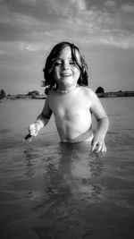 Portrait of smiling shirtless boy standing at sea against sky