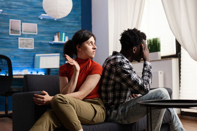 Couple arguing sitting on sofa at home