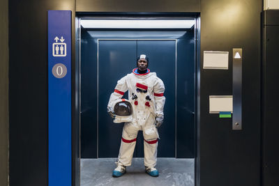 Male astronaut with space helmet standing in elevator