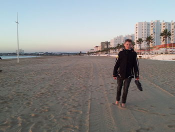 Full length of boy walking on sand against sky at beach