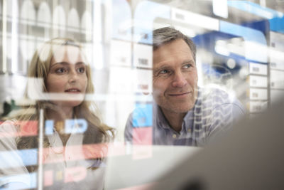 Man and woman looking at transparent touchscreen device
