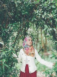 Woman standing by tree against plants