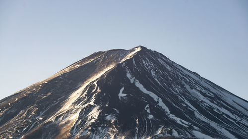 Low angle view of snowcapped mountain against clear sky