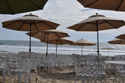 Deck chairs and umbrellas on beach against sky