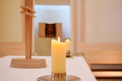 Close-up of illuminated candles on table at church