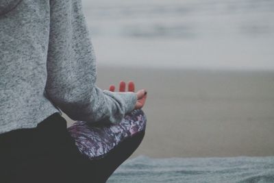 Midsection of woman sitting on sand at beach