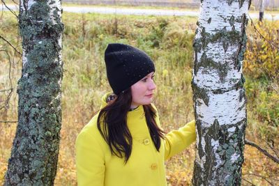 Young woman with tree trunk in forest