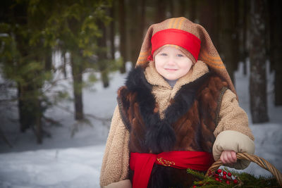 Portrait of young woman wearing warm clothing standing against trees