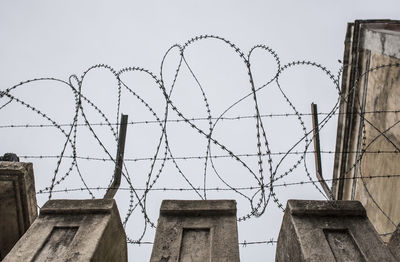 Low angle view of barbed wire fence against sky