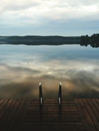 Pier on lake against cloudy sky