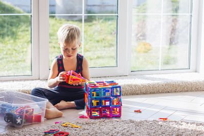 The child is playing with a multi-colored magnetic constructor, building a tower. educational toys 